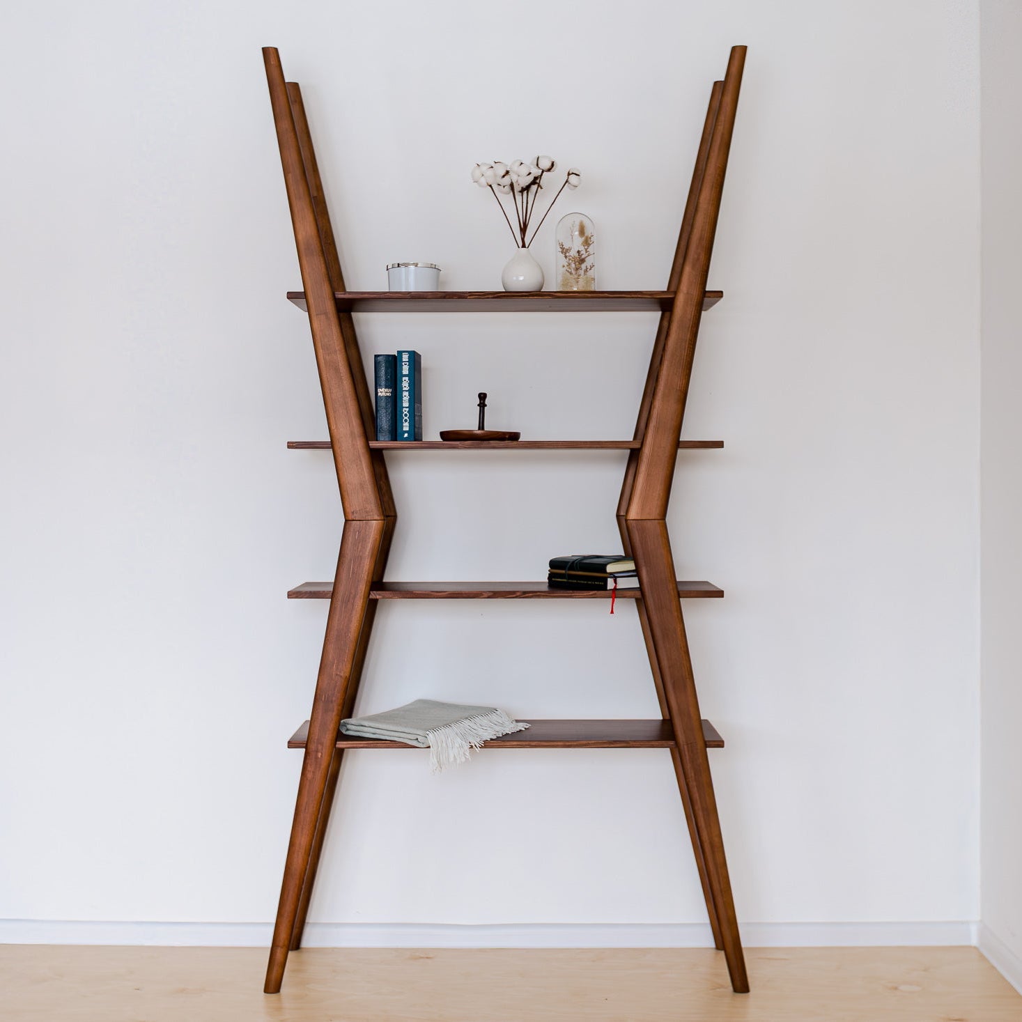 Wooden ladder shelf with decorative items against a white wall