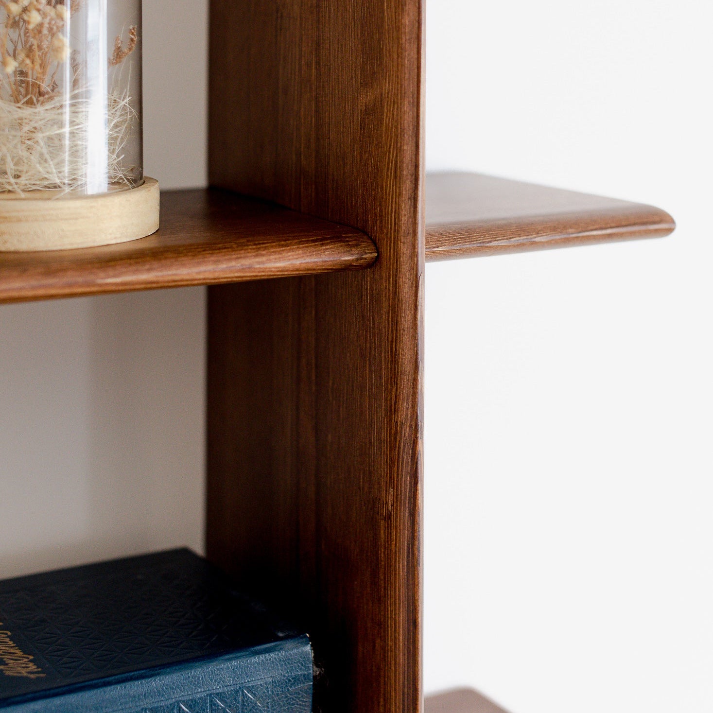 Wooden shelf with books and a decorative glass dome on a white background